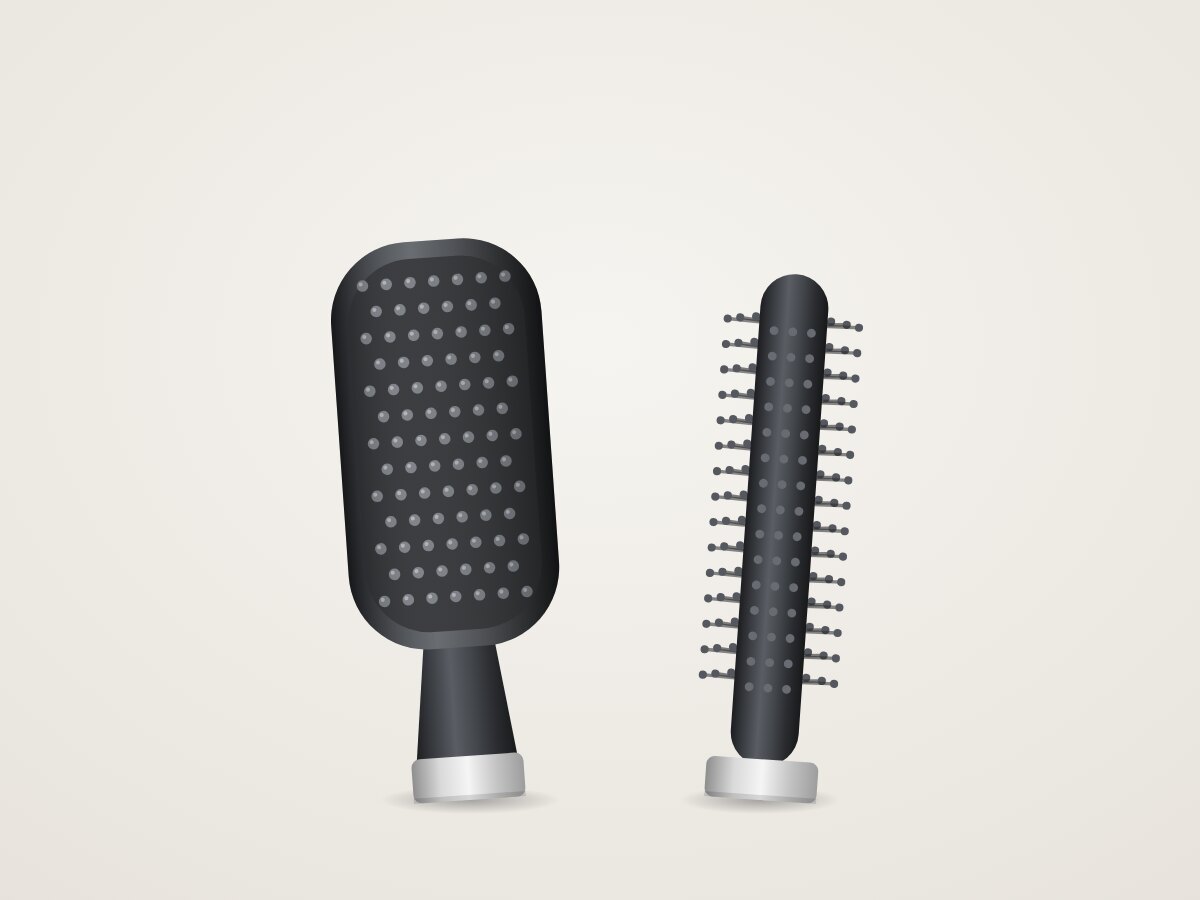 Graphite paddle brush with rows of rounded bristles beside a slim round brush